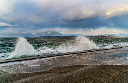 A vave explodes onto the sea wall at Alki Beach in West Seattle, Washington.の写真素材