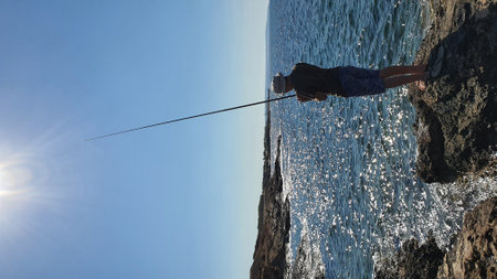 A man catches a fish with a fishing rod in the sea. High quality photoの写真素材