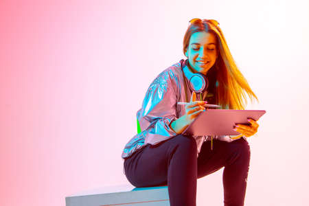 Modern Girl with laptop, tablet computer. Free creativity. A young blogger makes a Home office. Colored Neon light and background.の写真素材