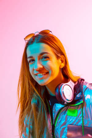 Modern Girl with laptop, tablet computer. Free creativity. A young blogger makes a Home office. Colored Neon light and background.の写真素材