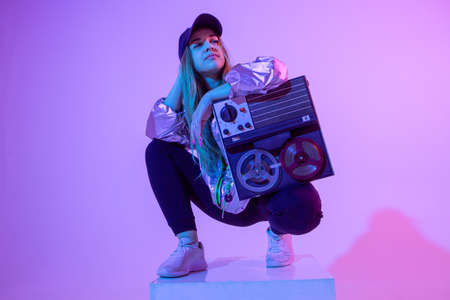 The girl with the record player. Colored background and neon light. Modern clothes. Music poster. Retro concept.の写真素材