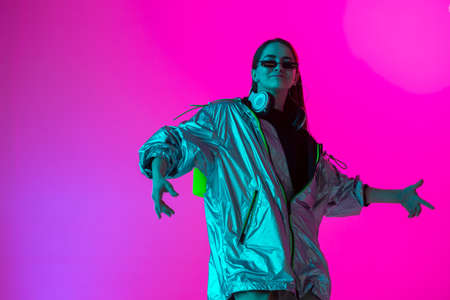 Young stylish girl dancing in the Studio on a colored neon background. Music poster design.の写真素材