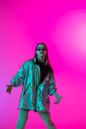 Young stylish girl dancing in the Studio on a colored neon background. Music poster design.の写真素材