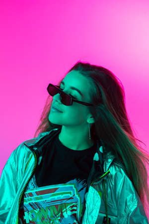 Young stylish girl dancing in the Studio on a colored neon background. Music poster design.の写真素材