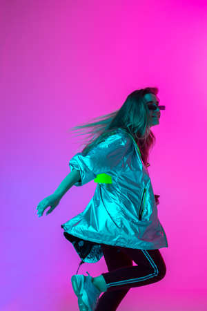 Young stylish girl dancing in the Studio on a colored neon background. Music poster design.の写真素材