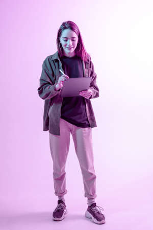 Modern Girl with laptop, tablet computer. Free creativity. A young blogger makes a Home office. Colored Neon light.の写真素材