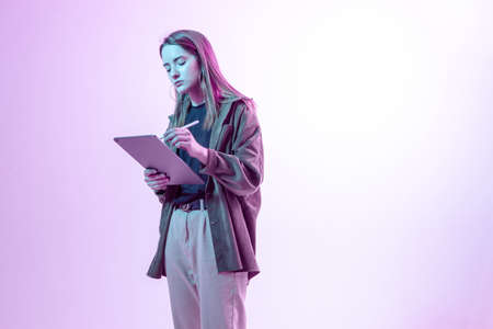 Modern Girl with laptop, tablet computer. Free creativity. A young blogger makes a Home office. Colored Neon light.の写真素材