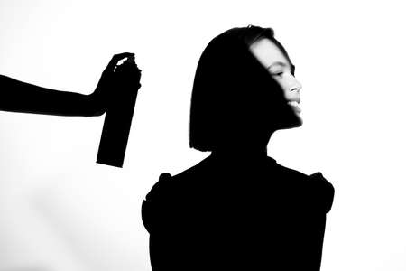 Black and white silhouette portrait with shadow and spot of light. The girl uses hairspray. Hair cosmetic concept.の写真素材