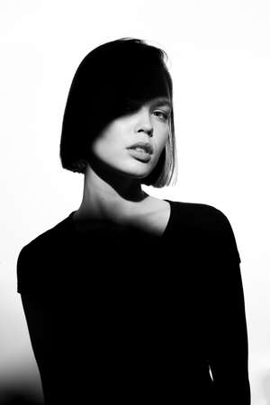 Fashionable beauty portrait. Black silhouette on white background. Girl with a spot of light on her face.の写真素材
