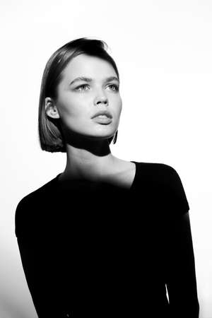 Fashionable beauty portrait. Black silhouette on white background. Girl with a spot of light on her face.の写真素材