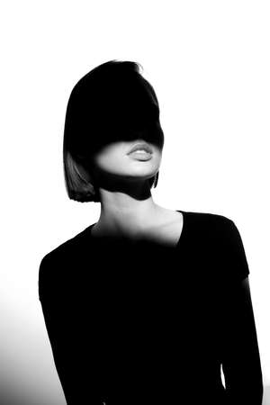 Fashionable beauty portrait. Black silhouette on white background. Girl with a spot of light on her face.の写真素材