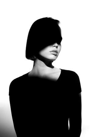 Fashionable beauty portrait. Black silhouette on white background. Girl with a spot of light on her face.の写真素材
