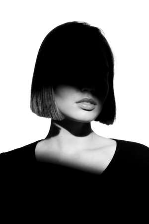 Fashionable beauty portrait. Black silhouette on white background. Girl with a spot of light on her face.の写真素材