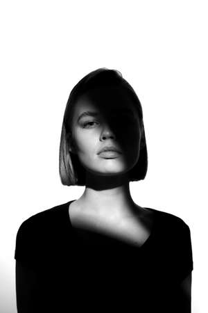 Fashionable beauty portrait. Black silhouette on white background. Girl with a spot of light on her face.の写真素材