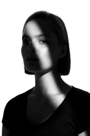 Fashionable beauty portrait. Black silhouette on white background. Girl with a spot of light on her face.の写真素材