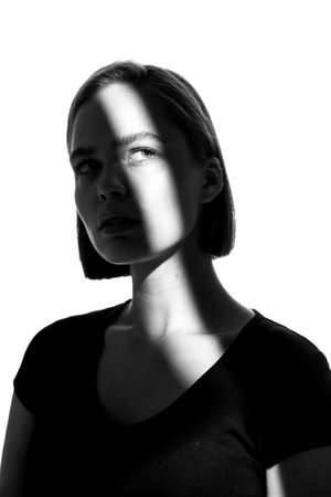 Fashionable beauty portrait. Black silhouette on white background. Girl with a spot of light on her face.の写真素材