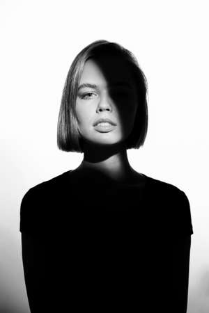Fashionable beauty portrait. Black silhouette on white background. Girl with a spot of light on her face.の写真素材