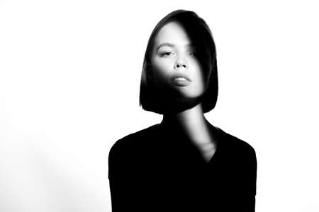 Fashionable beauty portrait. Black silhouette on white background. Girl with a spot of light on her face.の写真素材