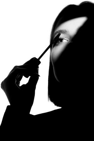 Epic promotional portrait of a girl with applicator and mascara brush. Black and white minimalistic advertising concept.の写真素材