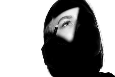 Portrait of a girl on a white background. Fashion model uses cosmetic pencil for eyebrows and eyelids. Black-white.の写真素材