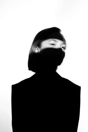 Fashionable beauty portrait. Black silhouette on white background. Girl with a spot of light on her face.の写真素材