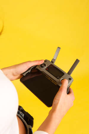 Teen girl launches aerial drone quadcopter. Isolated on a yellow background. Aerial photography.