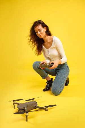 Teen girl launches aerial drone quadcopter. Isolated on a yellow background. Aerial photography.