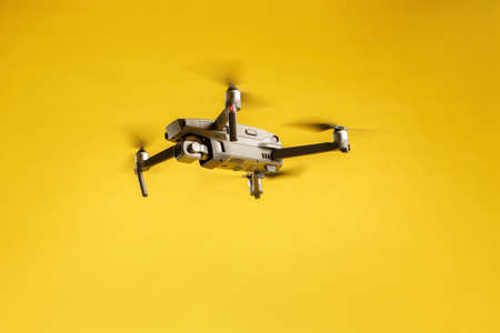 Air drone quadcopter isolated on yellow background in the air launched. Video and aerial photography from height.の写真素材