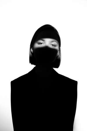 Fashionable beauty portrait. Black silhouette on white background. Girl with a spot of light on her face.の写真素材