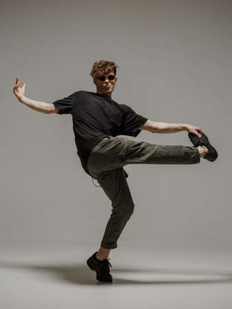 Guy dancing contemporary dance in studio. Neutral grey background. Acrobatic bboy dancer.