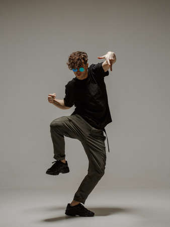 Guy dancing contemporary dance in studio. Neutral grey background. Acrobatic bboy dancer.の写真素材