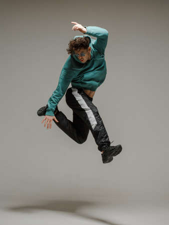 Guy dancing contemporary dance in studio. Neutral grey background. Acrobatic bboy dancer.