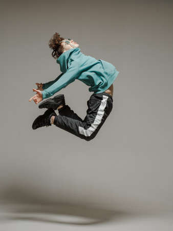 Guy dancing contemporary dance in studio. Neutral grey background. Acrobatic bboy dancer.の写真素材
