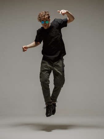 Guy dancing contemporary dance in studio. Neutral grey background. Acrobatic bboy dancer.