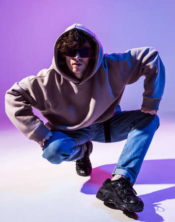 Breakdancing young man in hoodie with hair styling. Dance school poster. Copy space. Battle competition announcement.の写真素材