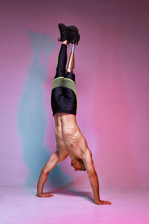 A young muscular man with a disability with a prosthetic leg, stands in his hands. Motivation posterの写真素材