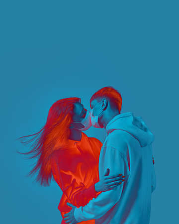 Boy and girl kiss. Medical protective mask on face. Fear of virus infection. Modern poster design with copy space.の写真素材