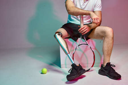 A young man with a disability with a prosthetic leg play in tennis. Motivation posterの写真素材