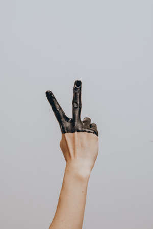 Elegant female hand dipped in black paint on a light background. Isolated. Gestureの写真素材