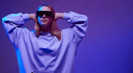 Portrait of a stylish young girl, cool posing in a hoodie, sunglasses and with developing hair, on a...