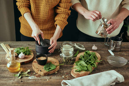 Young married couple prepare by grinding spices in a mortar during the cooking process, fresh ingredients on table.の写真素材