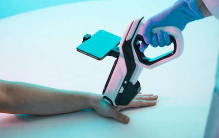 Doctors hand makes an injection chip, a modern syringe with scanner, into hand of a man, chipization of the population.の写真素材