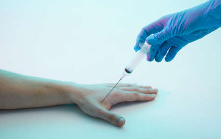 The doctors hand makes an injection with a chip, a syringe, in the hand, a young man, chipization of the population.の写真素材