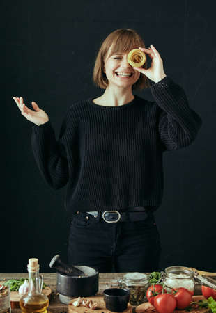 Portrait of a happy girl closes eye with a nest of spaghetti macaroni with a smile on a black...