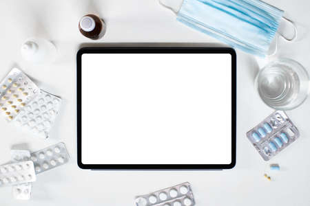 A tablet with an empty screen is lying on the table among medications medical supplies tablets and a...