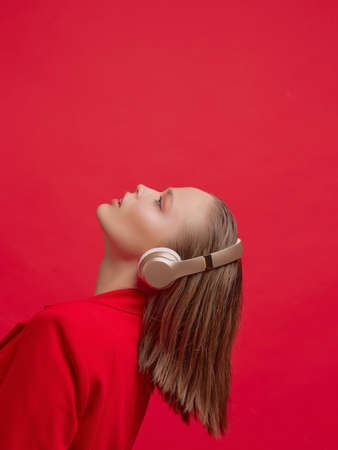 A beautiful young girl in wireless headphones listens to song with a good mood. bright colorful music poster.の写真素材