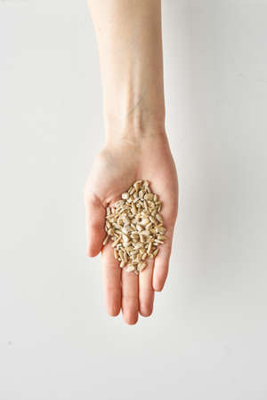 100 calories portion of snack of sunflower seeds in hand isolated on white background, healthy food...