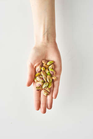 100 calories of healthy snack of pistachios in hand isolated on a white background, healthy food and lifestyle. High quality photoの写真素材
