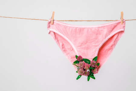 Pink womens underwear decorated with flowers on clothesline isolated on white, concept photography...
