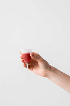 Menstrual cup eco friendly reusable and silicone in womans hand with menstrual fluid isolated on a white backgroundの写真素材